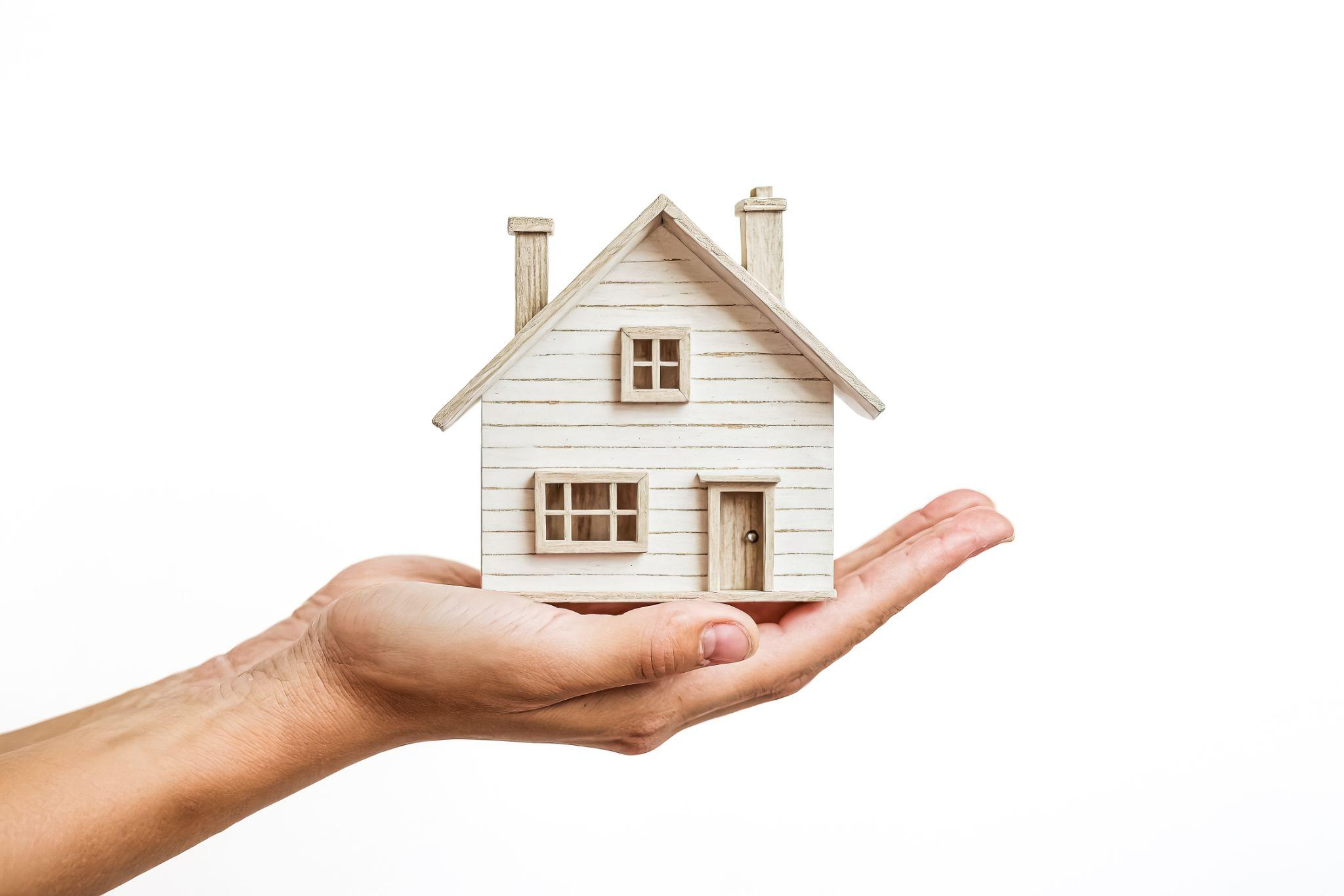 A hand holding a model house